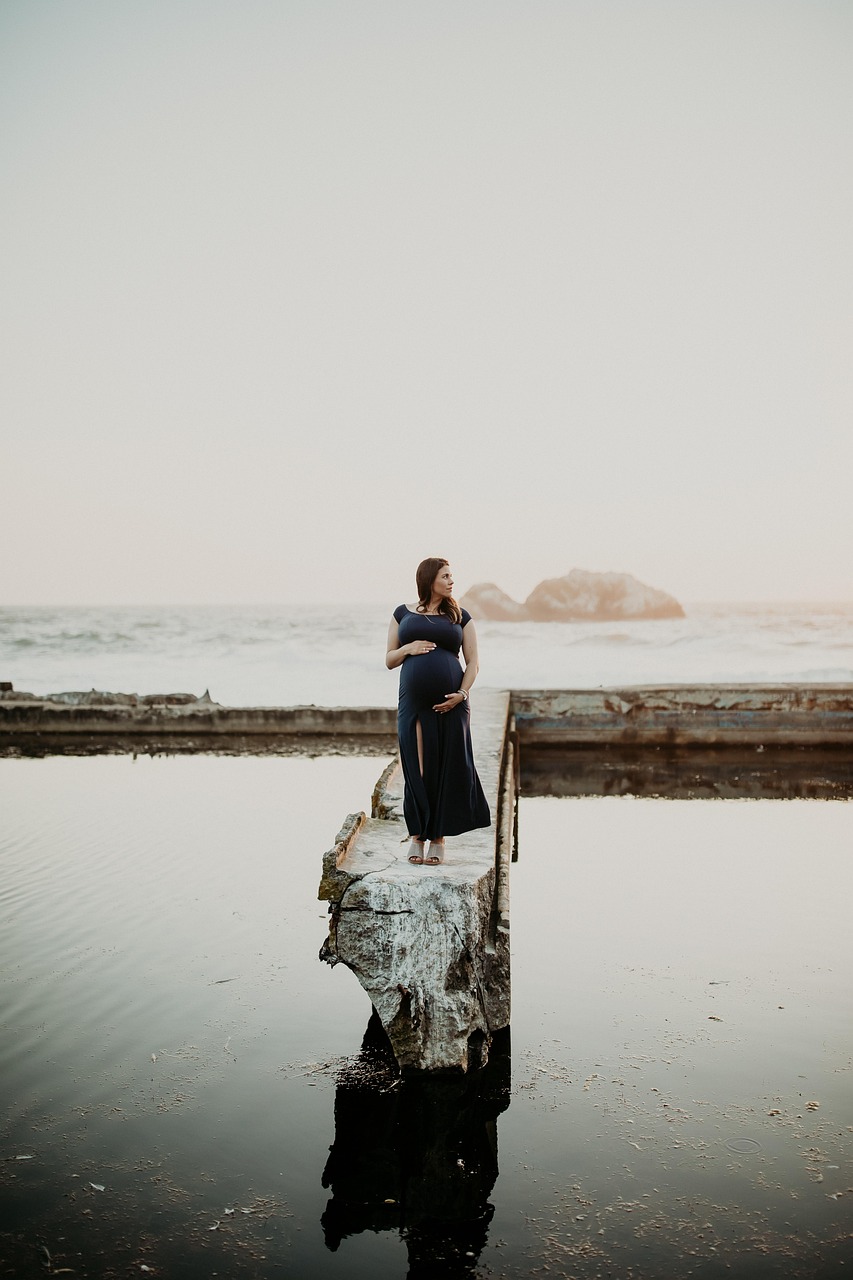 Femme seule au bord de la mer, évoquant la grossesse après une perte et le mélange d'espoir et d'anxiété du deuil périnatal